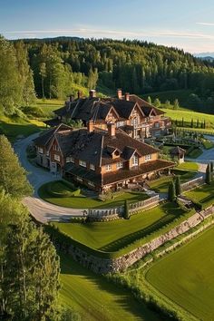 an aerial view of a large house in the middle of a lush green field with trees