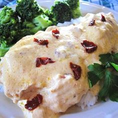 a white plate topped with chicken covered in sauce and broccoli florets