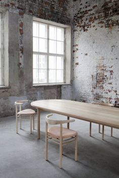 an empty table and two chairs in front of a window with brick wall behind it