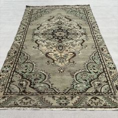 an antique rug is laying on the floor in front of a white wall and carpet