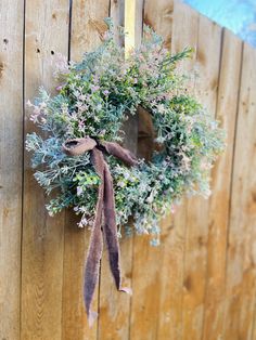 a wreath hanging on the side of a wooden fence