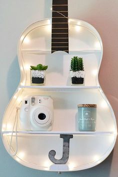 a guitar shaped shelf with some plants and a camera