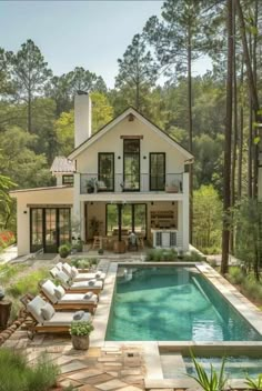 a house with a swimming pool in front of it and lots of furniture around the pool