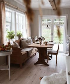 a living room filled with furniture next to a wooden table and window covered in curtains