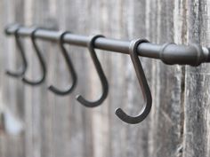 three metal hooks are hanging on a wooden wall