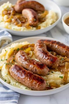 two plates with sausages and mashed potatoes on them