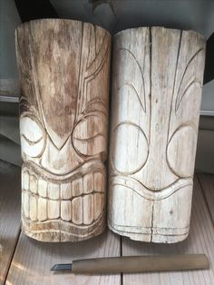 two carved wooden vases sitting on top of a table next to a pen and pencil