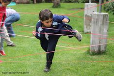 a young boy is jumping over a rope in the grass with other children behind him