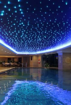 an indoor swimming pool with blue lights on the ceiling and water in the pool area