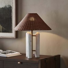 a table lamp sitting on top of a wooden dresser next to a book and magazine