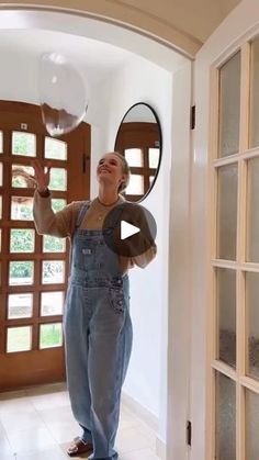 a woman standing in front of a doorway holding a mirror and blowing bubbles into the air