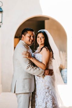 a bride and groom pose for a photo in front of an archway at their wedding