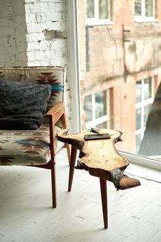 a chair sitting next to a window with a wooden table on it's side