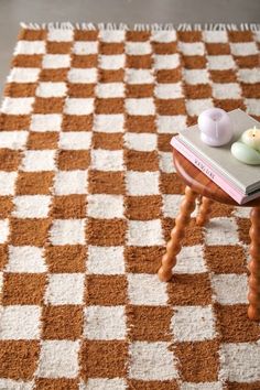 an orange and white checkered rug with two small stools on top of it