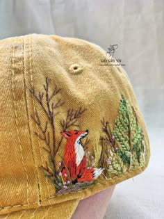 a close up of a baseball cap on a person's head with trees and birds embroidered on it