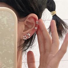 a woman is holding her ear with three stars in the shape of an earring