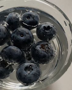 blueberries are in a glass bowl with water