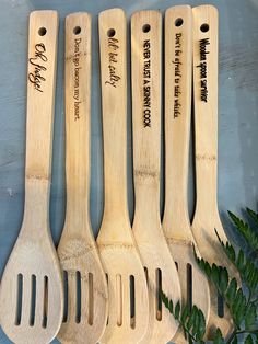 five wooden spoons with names on them sitting next to a potted green plant