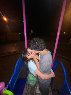 two people are kissing on a carousel at night