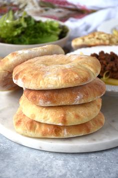 several pastries stacked on top of each other in front of a bowl of salad