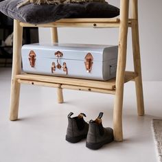 a white suitcase sitting on top of a wooden chair next to a pair of shoes