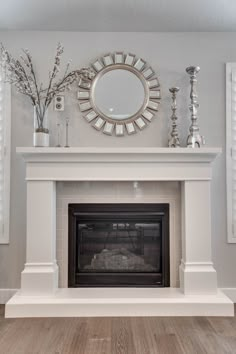 a white fireplace with a mirror above it