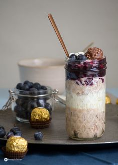 a glass jar filled with blueberry cheesecake in front of other desserts on a tray