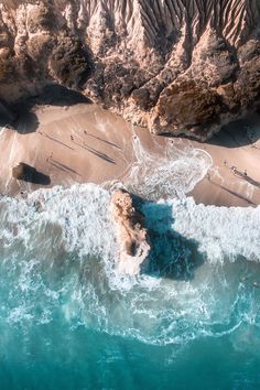 an aerial view of the beach and ocean with waves crashing on it's shore