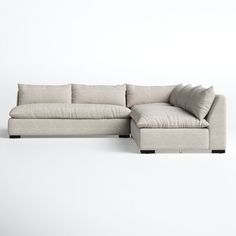 a large sectional couch with pillows on the top and bottom, sitting in front of a white wall