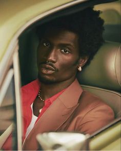 a man with an afro sitting in a car