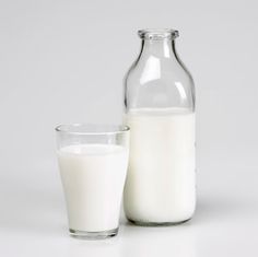 a glass and bottle of milk sitting next to each other