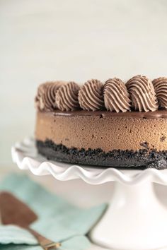 a cake with chocolate frosting and cookies on top is sitting on a white pedestal