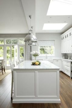 a large kitchen with white cabinets and an island in front of the stove top oven