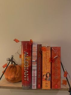 a shelf with books and a pumpkin on it