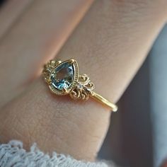 a close up of a person's hand wearing a gold ring with an aqua blue stone