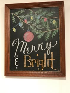 a chalkboard with the words merry and bright written on it in front of a christmas tree