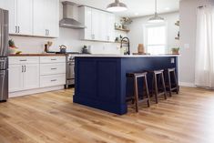 a kitchen with white cabinets and blue island