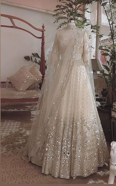 a dress on display in a room with a bed and window behind it that is decorated with sequins