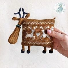 a hand is holding up a small knitted bag with a deer on it and two antlers sticking out of the side