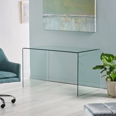 a glass table in the middle of a room next to a chair and potted plant