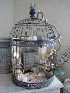 a bird cage sitting on top of a table filled with drawers and other things in it