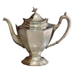 an antique silver teapot on a white background