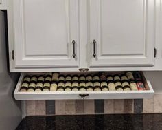 a kitchen with white cabinets and black granite counter tops, under the cabinet is an open spice rack