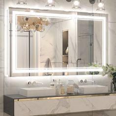 a bathroom vanity with two sinks and a large mirror over the sink that has lights on it