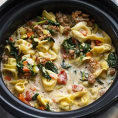 a crock pot filled with pasta and spinach