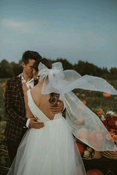 a bride and groom standing in a pumpkin field