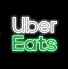 the words uber eats are lit up in green and white