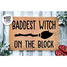 a door mat with the words badest witch on the block and a pair of red shoes