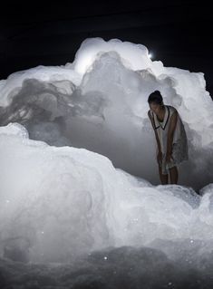 a man standing in an ice cave with snow piled all around him and looking at the ground