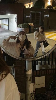 a woman taking a selfie in front of a mirror with another person standing behind her